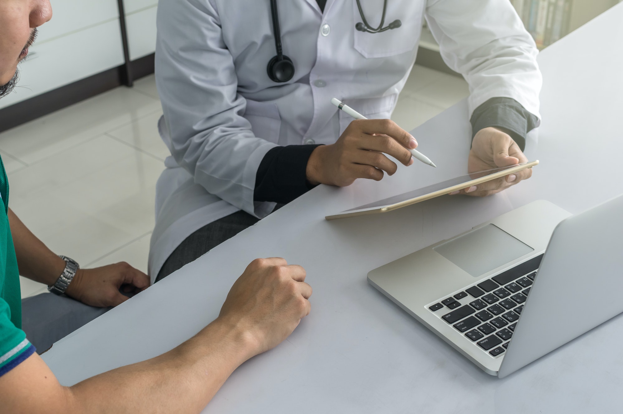 Doctor is consulting with Patient about his health on working desk